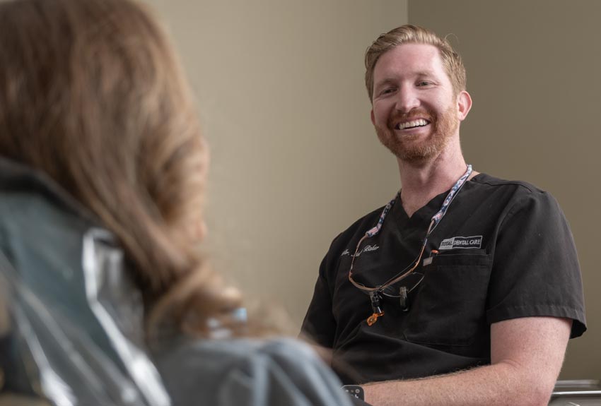 Dr. Austin Baker talking with a patient in an exam room.
